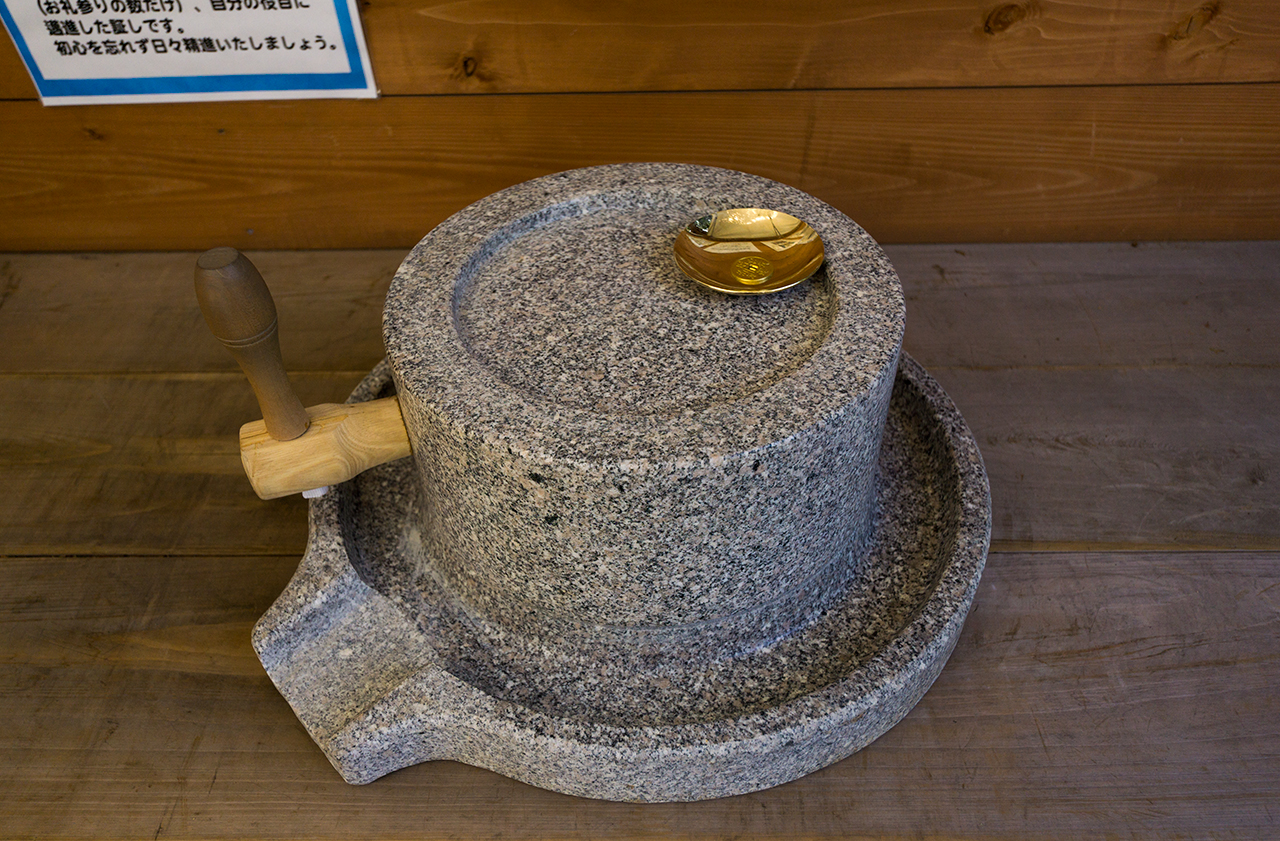 金杯を乗せた銭回しの石臼